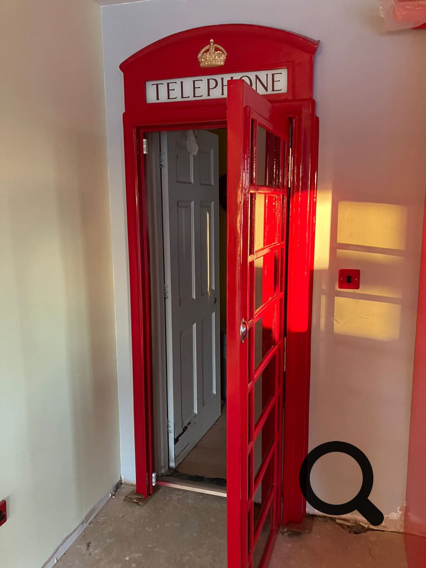 Rote Telefonzelle Tür mit geöffneter Tür in einem Innenraum.